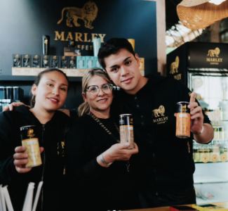 Lámina 2 de 3: Tres promotoras con latas de Marley Coffee